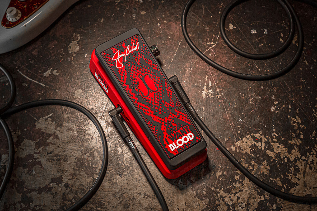 Pédale Wah Dunlop Cry Baby Jerry Cantrell I Want Blood édition signature rouge et noire, posée sur une surface usée de type atelier avec des câbles de guitare enroulés autour.