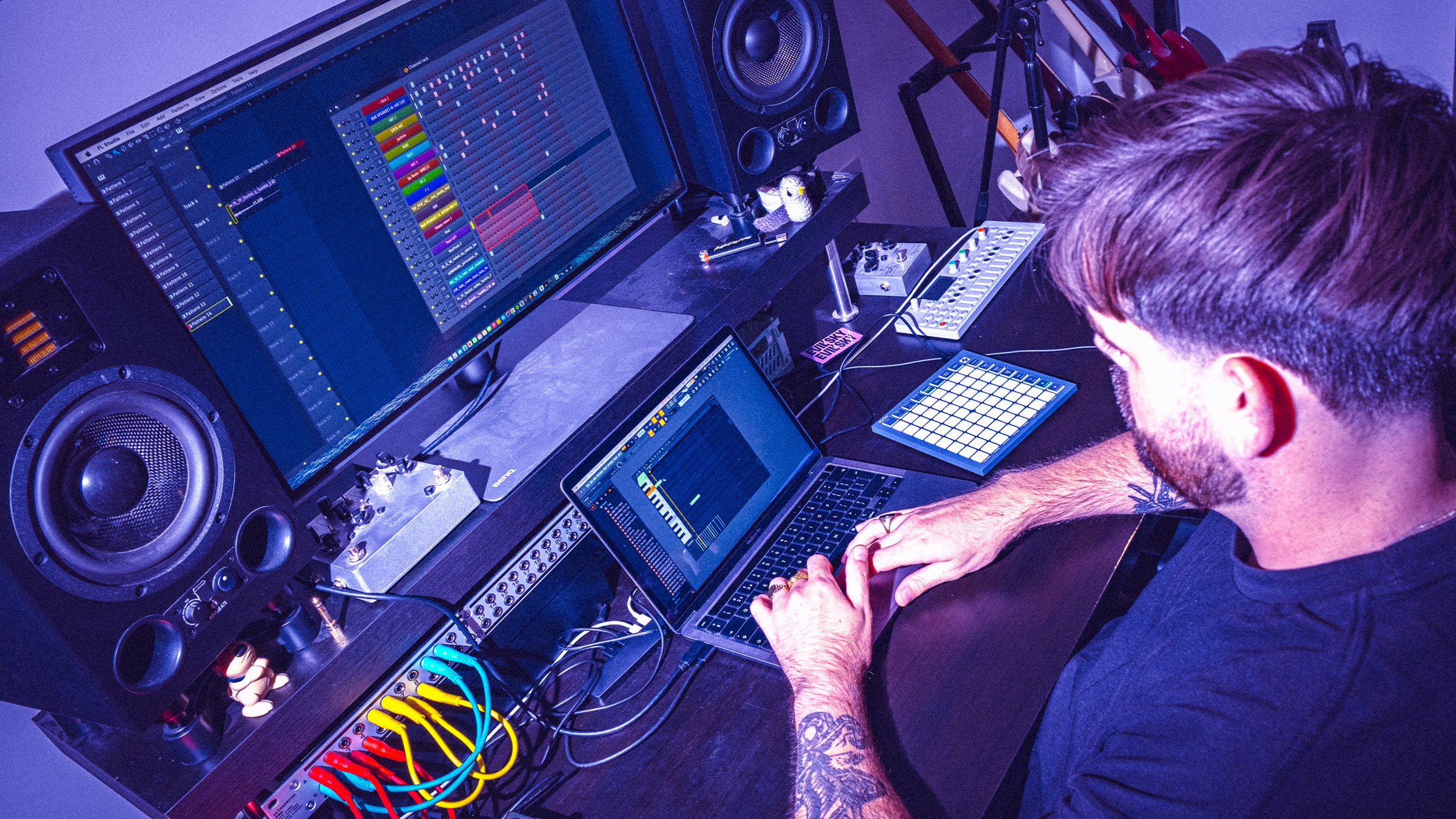 Un producteur de musique utilisant un ordinateur portable et un contrôleur MIDI lumineux pour composer sur un logiciel de production audio