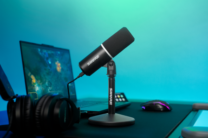 Microphone Shure MV6 Gen 2 noir sur son pied de bureau, installé devant un ordinateur portable dans un setup gaming.
