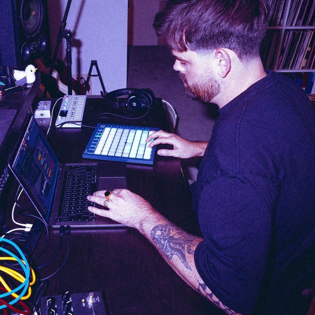 Musicien utilisant un contrôleur MIDI et un ordinateur dans un studio.