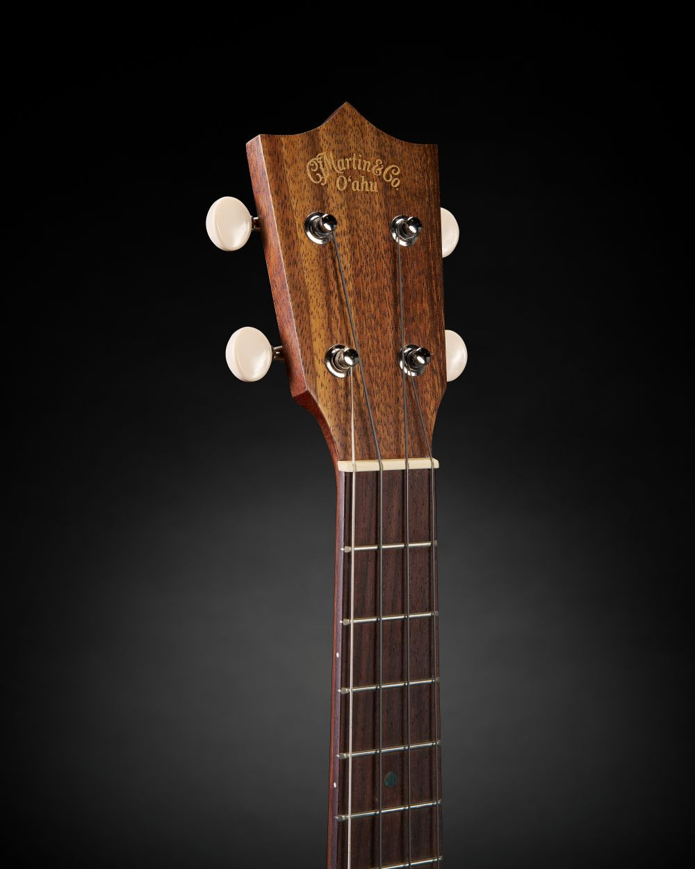 Ukulélé Martin O’ahu TKE Uke Burst avec une finition bois verni en dégradé, présenté sur un fond noir uni.