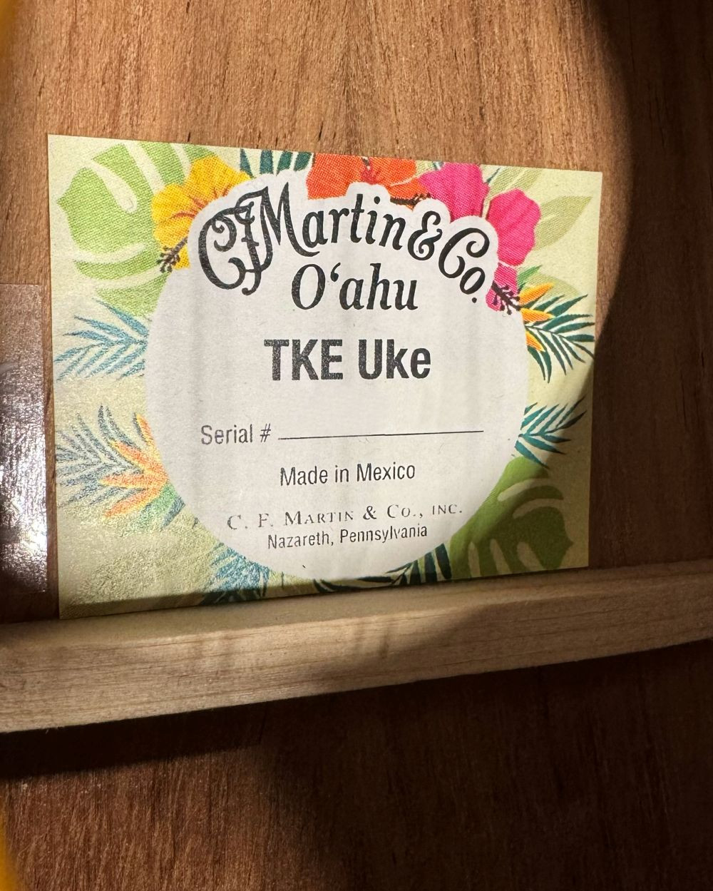 Ukulélé Martin O’ahu TKE Uke Burst avec une finition bois verni en dégradé, présenté sur un fond noir uni.
